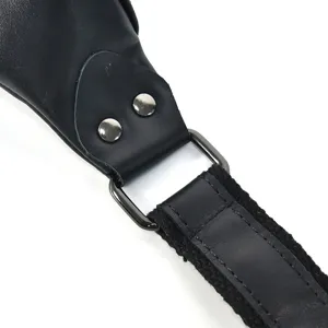 Detailed view of the black leather bag strap attachment, metal hardware and buckle.