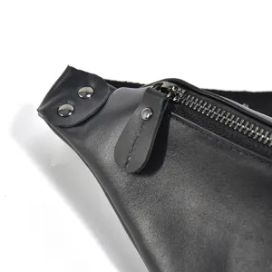 Detailed view of the black leather waist bag, highlighting the metal zipper and rivets.