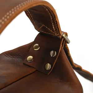 Close-up view of vintage genuine crazy horse leather bag strap detail with sturdy metal rivets.