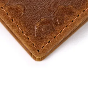Close-up detail of vintage genuine leather men's wallet corner with neat stitching texture.
