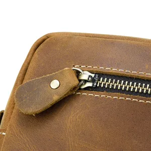 Close-up detail of genuine leather toiletry bag zipper and vintage stitching craftsmanship.