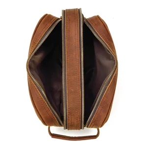 Genuine leather toiletry bag detail showing double zipper compartments and vintage texture.