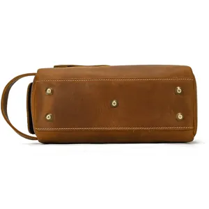 Vintage crazy horse leather toiletry bag bottom detail showing brass feet and sturdy handle.