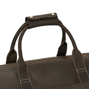 Genuine leather travel bag handle detail, premium brown duffel bag craftsmanship closeup.