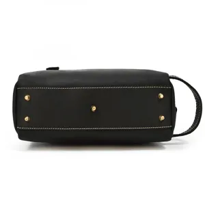 Black leather toiletry bag detail view showing metal bottom feet and contrast stitching.