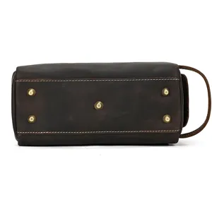 Leather toiletry bag bottom detail view showing metal feet and durable stitching craftsmanship.