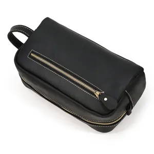 Black genuine leather dopp kit with side handle and gold zipper for men toiletries storage.