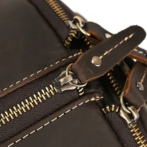 Detailed view of genuine leather travel duffel bag zipper, vintage metal hardware and stitching.