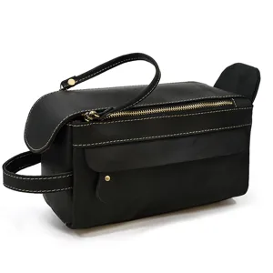Detail view of black leather toiletry bag with zipper and handle, showcasing fine stitching.