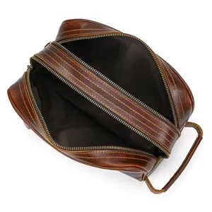 Detailed view of genuine leather toiletry bag with double zippers and side handle design.