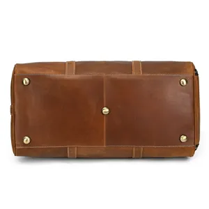 Leather duffel bag bottom detail showing sturdy metal feet, durable stitching, and fine texture.