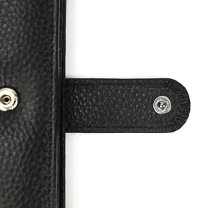 Close-up detail of the black genuine leather passport wallet snap closure and stitches.