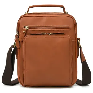 Detailed view of the leather crossbody bag featuring sturdy metal zippers and brown strap.