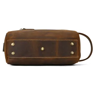 Detailed bottom view of vintage brown leather toiletry bag with durable metal protective feet.