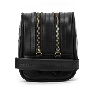 Close-up of black genuine leather toiletry bag, dual metal zippers and sturdy handle.