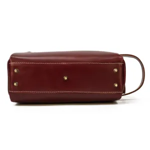Close-up detail of genuine leather toiletry bag bottom with metal feet and side handle.