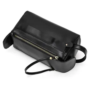 Black leather toiletry bag close-up showing metal zipper, handle, and premium texture detail.