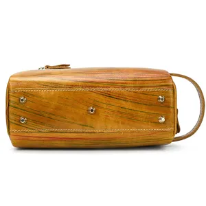Vintage leather toiletry bag bottom detail featuring protective metal feet and durable stitching.