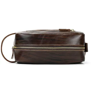 Close-up view of genuine leather toiletry bag with double zippers and side handle, vintage brown.