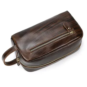 Detail view of dark brown leather toiletry bag with wood grain texture, zipper and side handle.