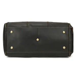 Leather travel duffel bag bottom detail showing durable metal feet and premium brown leather craft.