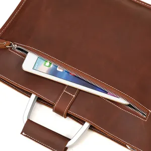 Vue de détail du cartable d'affaires en cuir marron avec poignée en métal et poche zippée.