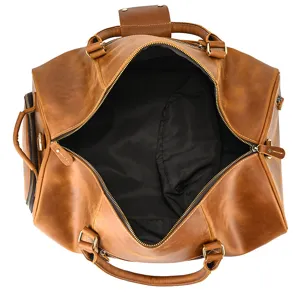 Detail view of the open brown leather travel duffel bag, showing interior lining and durable build.
