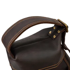 Close-up detail of vintage brown crazy horse leather messenger bag strap, metal rivets, and contrast stitching.