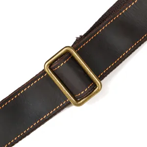 Detailed shot of dark brown leather bag strap with contrast orange stitching and brass buckle.