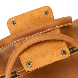 Detail view of vintage crazy horse leather travel bag handle and durable metal snap buttons.