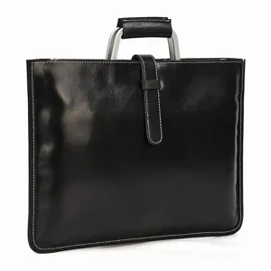 Détail de la mallette en cuir noir avec poignée en métal, bride verticale et coutures blanches.