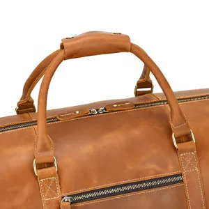 Detailed view of genuine crazy horse leather travel duffel bag handle and metal zippers.