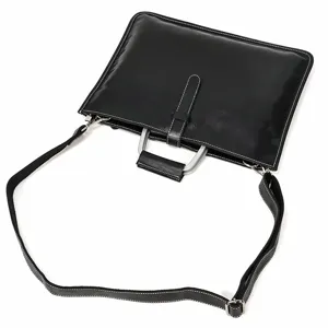 Vue détaillée du cartable d'affaires homme en cuir noir avec poignée métal et bandoulière.