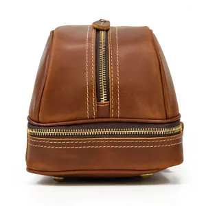 Leather toiletry bag detail showing double compartments, metal zippers, and fine stitching.