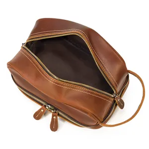 Close-up detail of vintage brown genuine leather dopp kit with dual zippers and side handle.