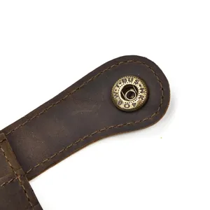 Gros plan détaillé d'un portefeuille en cuir vintage crazy horse avec bouton-pression en laiton.