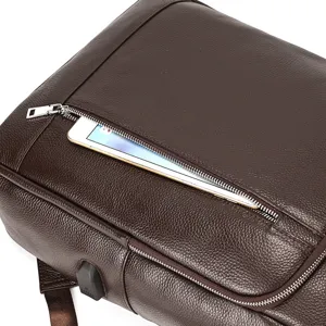 Leather backpack detail view showing front zipper pocket and USB charging port design.
