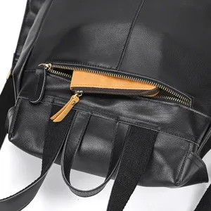 Close-up detail of black leather backpack featuring zipper pocket, durable straps and stylish pull.