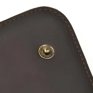 Gros plan détaillé du portefeuille en cuir marron foncé avec coutures et bouton-pression.