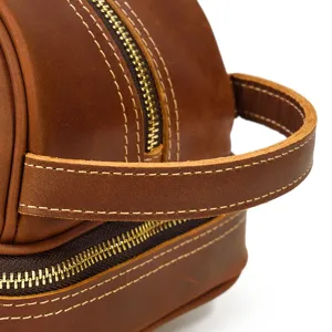 Close-up detail of vintage crazy horse leather travel toiletry bag with durable golden zippers.