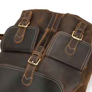 Close-up detail of vintage crazy horse leather backpack front pockets and brass metal buckles.