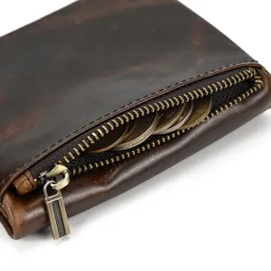 Close-up view of vintage brown leather wallet zipper coin pocket with metallic hardware.