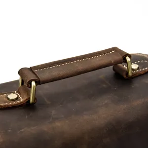 Dettaglio della maniglia della borsa fotografica in vera pelle con texture vintage e dettagli in ottone.