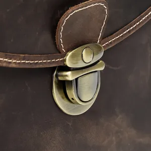 Primo piano di una borsa fotografica in vera pelle con serratura metallica e cuciture.