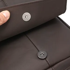 Primer plano detallado del bolso de cuero marrón que muestra el cierre de botón magnético.