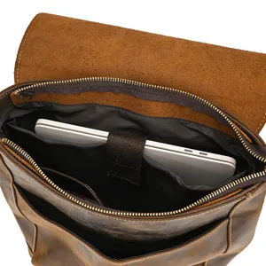 Close-up of vintage leather backpack interior with padded laptop compartment and secure strap.