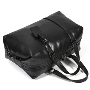 Black leather travel duffel bag detail showing durable dual handles and metal zippers.