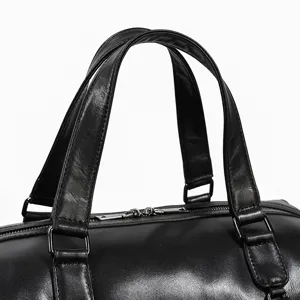 Close up of black leather travel bag handle and sturdy metal zipper hardware detail.