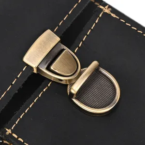 Close-up detail of the retro brass metal push lock on black leather phone waist bag.