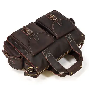 Vintage brown leather briefcase detail close-up showing multiple pockets and stitching.